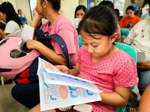 Little girl reading a booklet