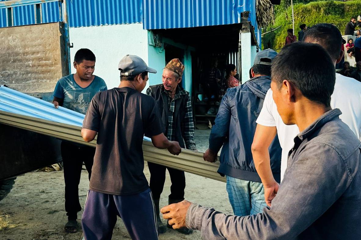 Local residents assist the response team in moving roofing sets for distribution.