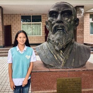 Chinese teenage girl by a stone statue.