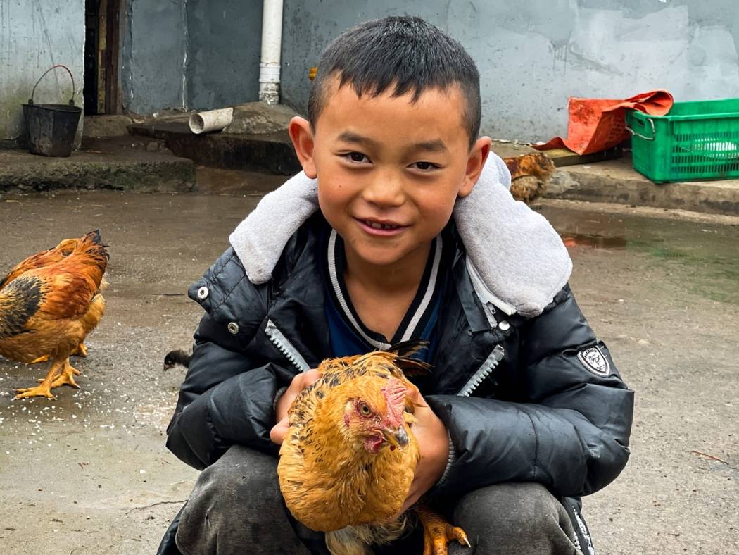 Beneficiary's son holding a chicken