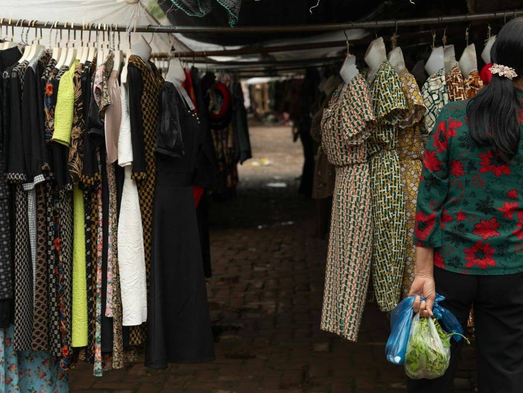 A woman is looking at clothes in a market