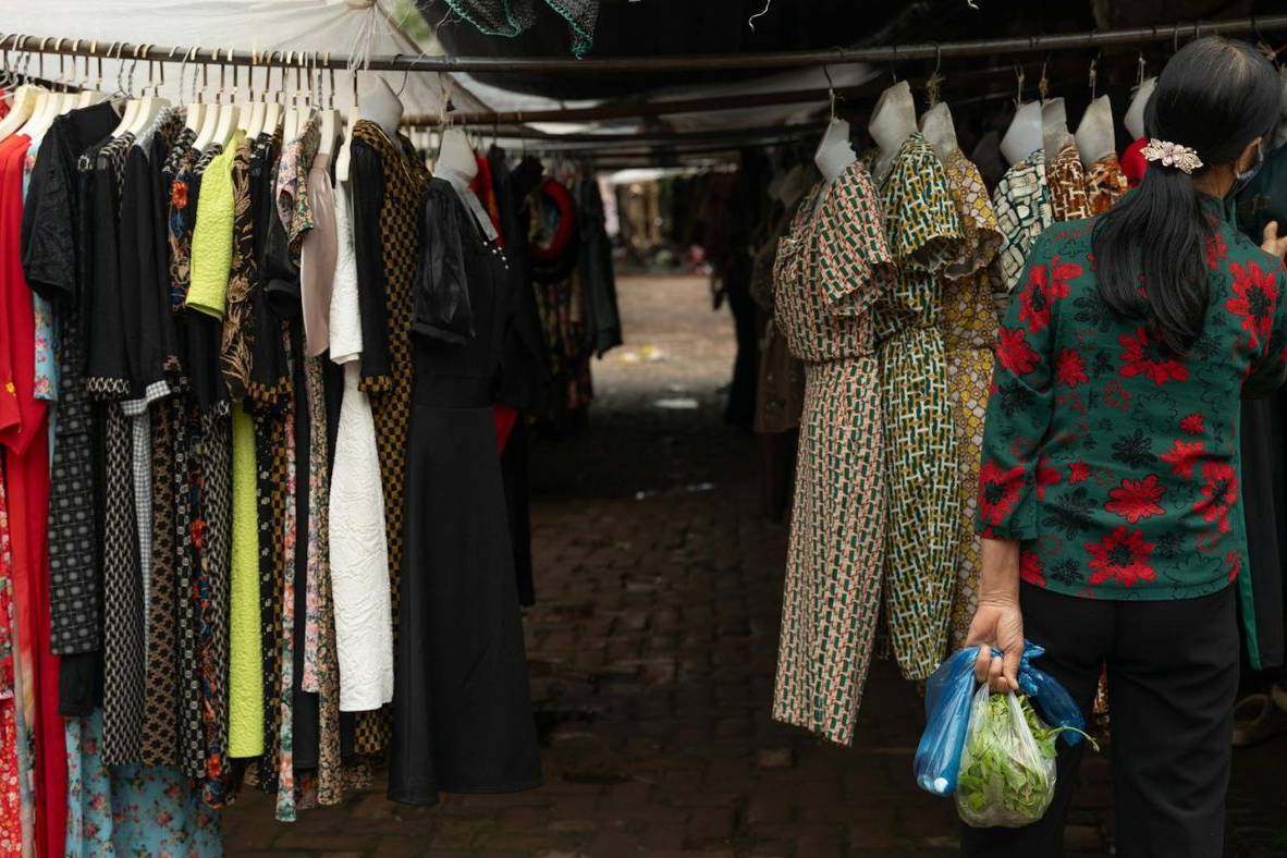 A woman is looking at clothes in a market