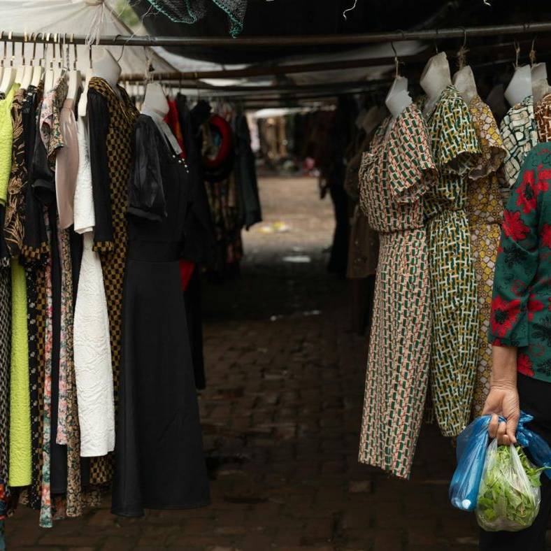 A woman is looking at clothes in a market