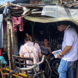 Filipino staff talking to a woman in her home in the slums