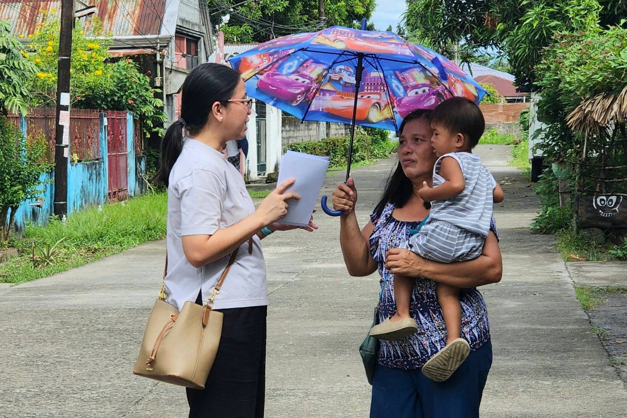 Filipino staff member talking to a mother carrying her child.