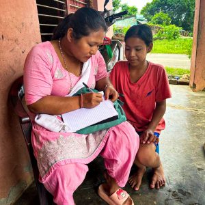 Woman writing on her notebook while a girl looks on