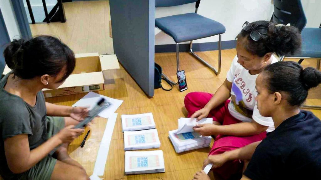 Three Filipino women making booklets