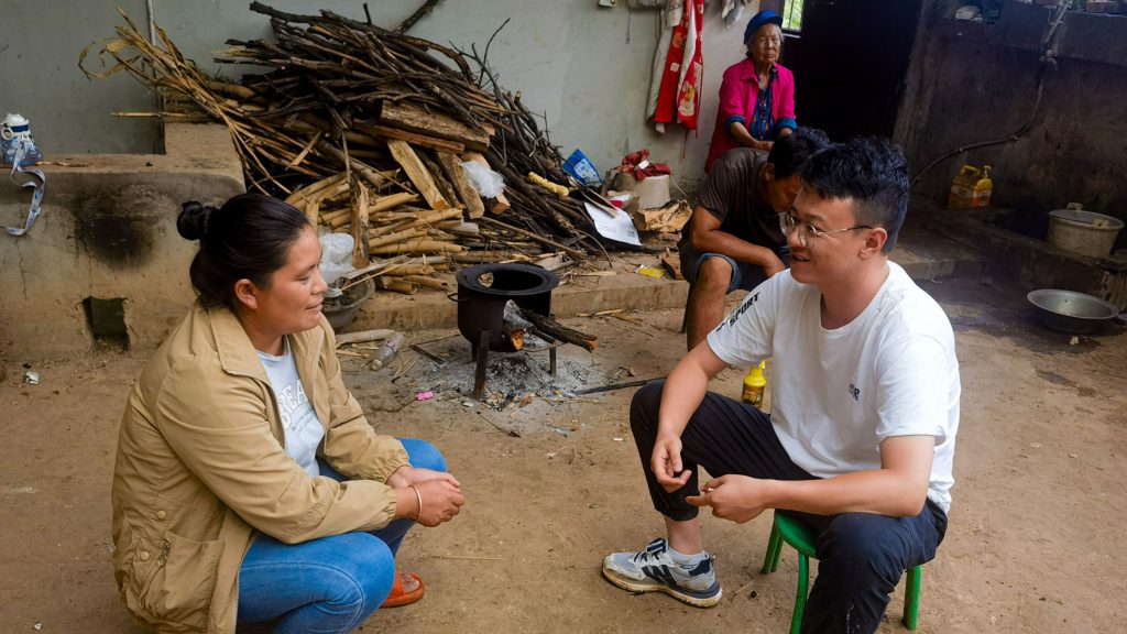 Man interviewing a Chinese woman in their yard.