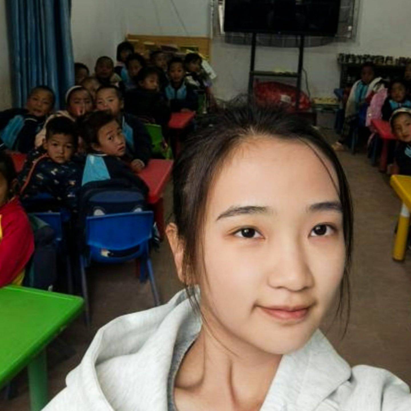 Chinese teacher posing for a photo with her preschool students in a classroom