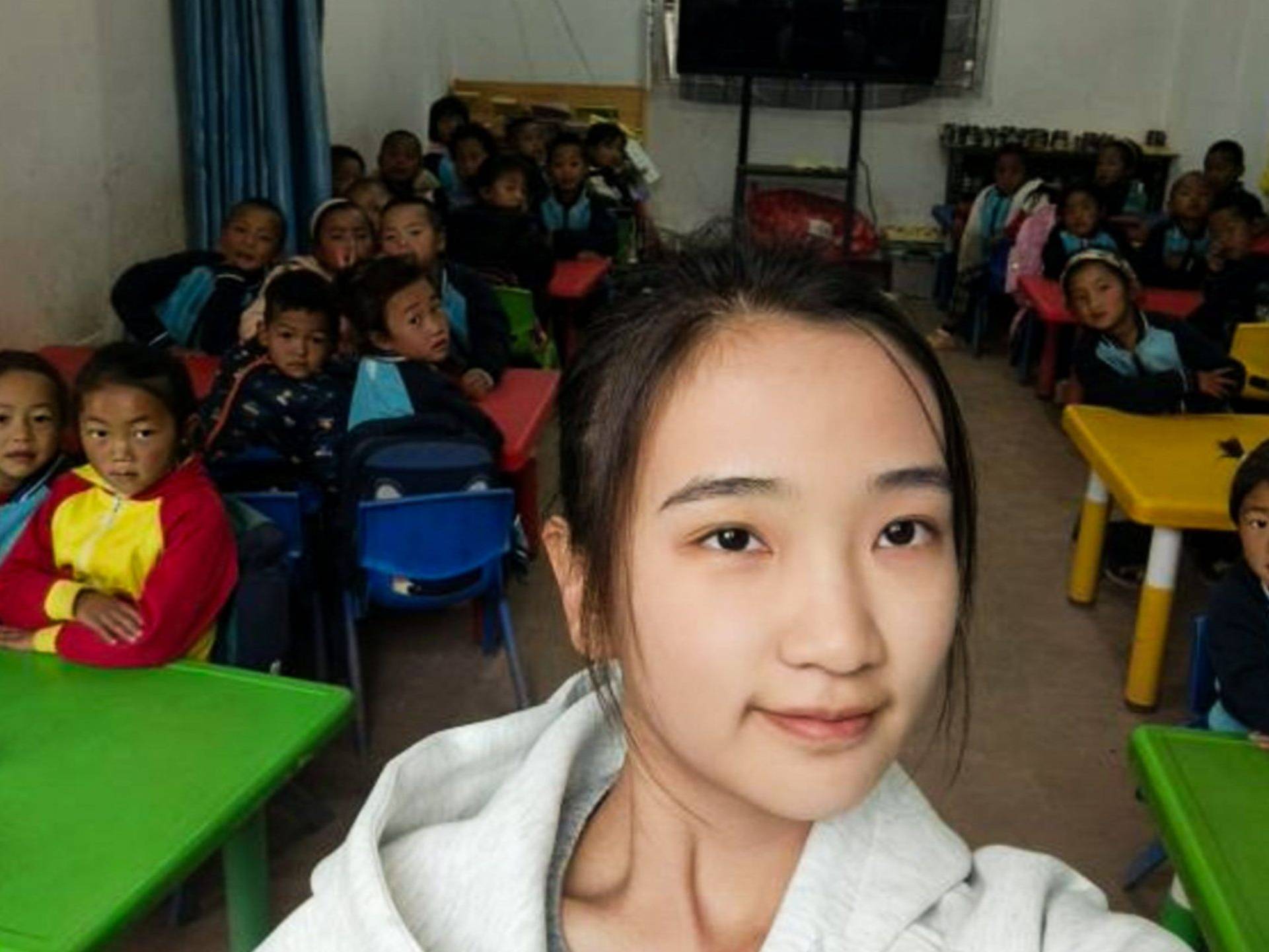 Chinese teacher posing for a photo with her preschool students in a classroom