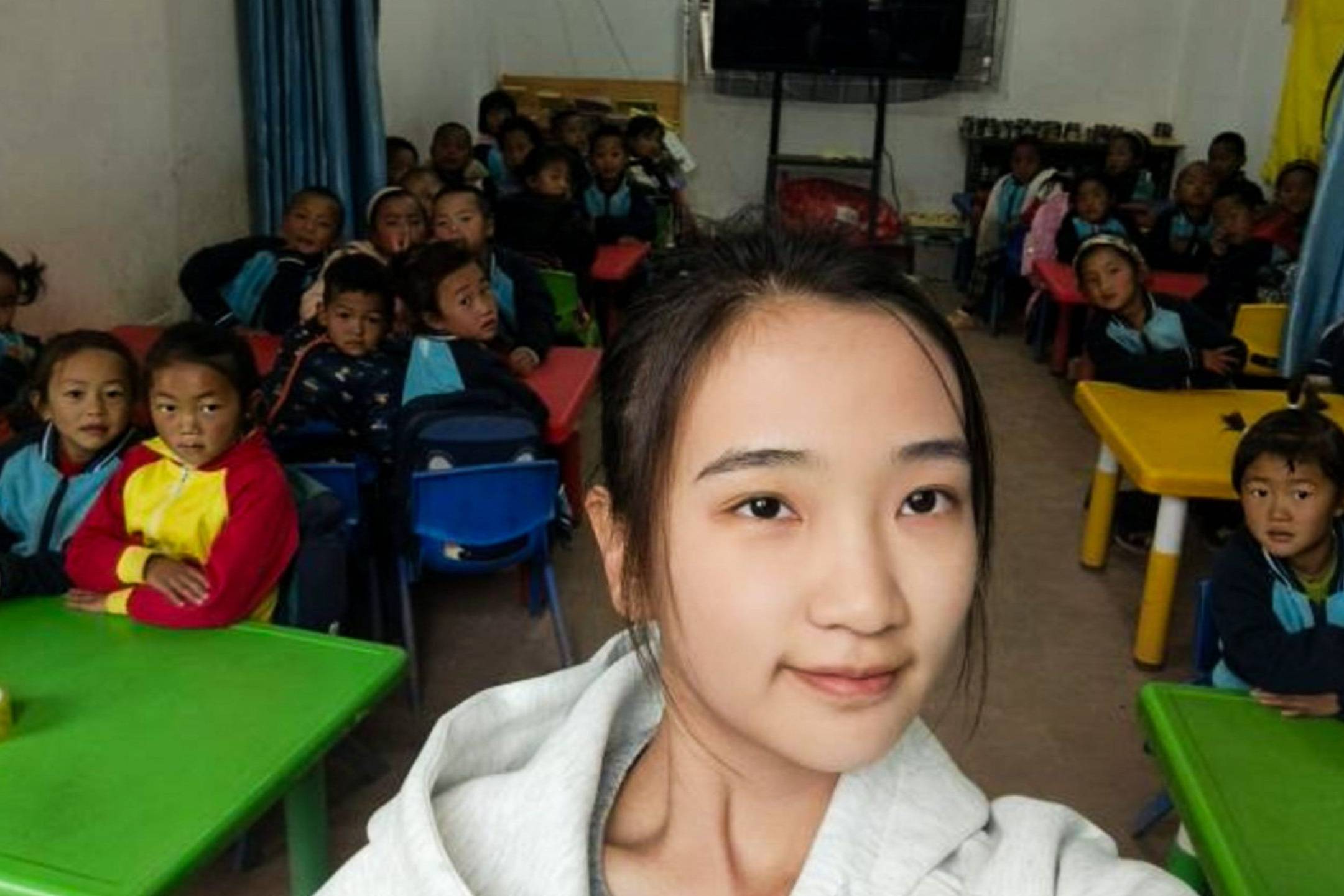 Chinese teacher posing for a photo with her preschool students in a classroom