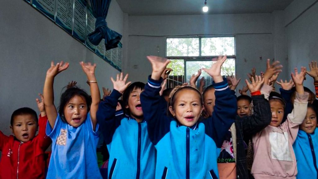 Chinese preschool students holding their hands up