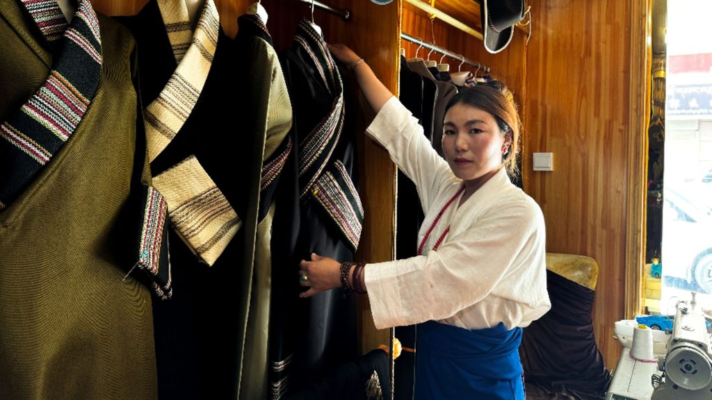 Woman arranging traditional garments in a clothing store.