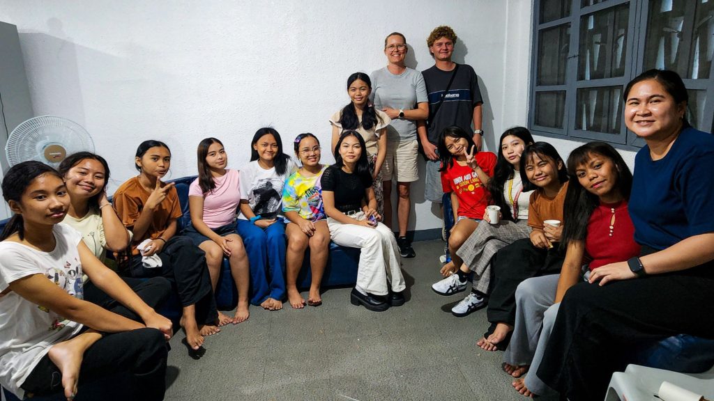 A diverse group of people sitting together on a couch in a bright room.