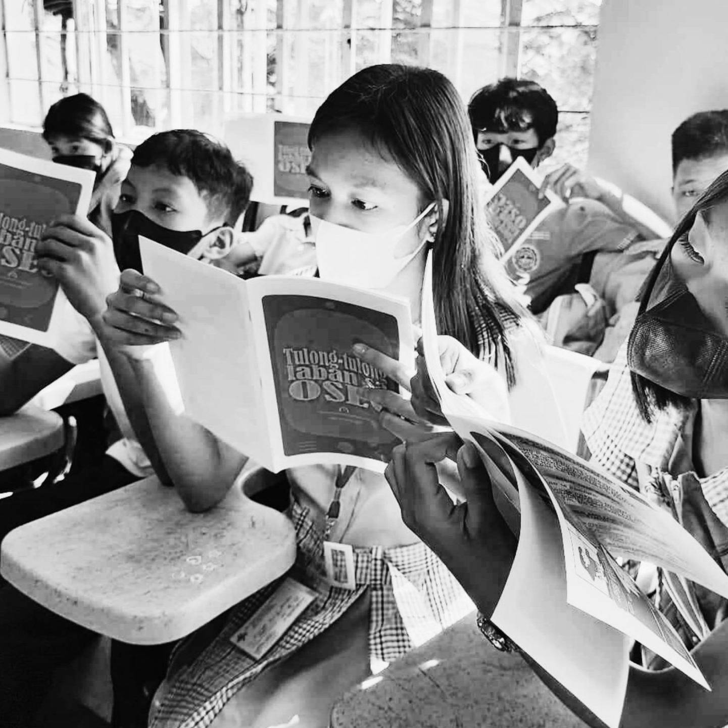 Students in a classroom attentively reading materials about online safety.