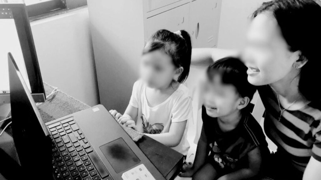 A woman and two children engaging with educational content on a laptop.