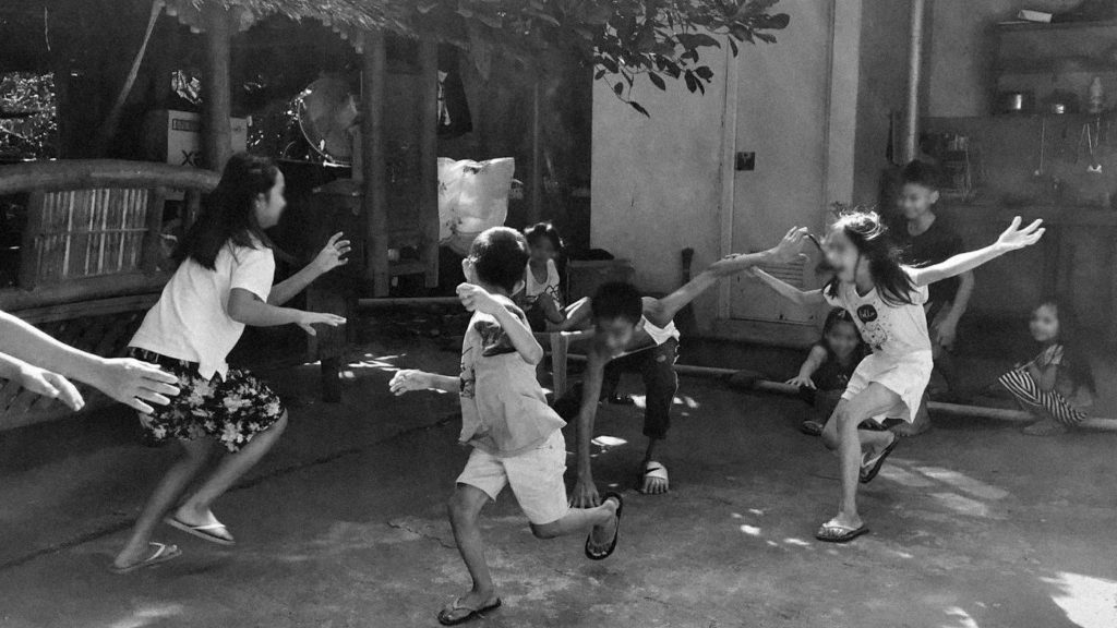 Children joyfully playing a traditional outdoor game in a rural setting.