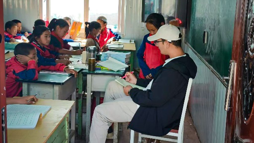 A male teacher engaging with students in a classroom.