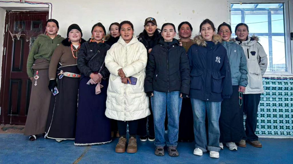 A group of women posing together indoors, wearing a mix of traditional and modern winter clothing.