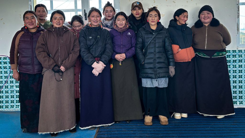 A group of women posing together indoors, wearing a mix of traditional and modern winter clothing.