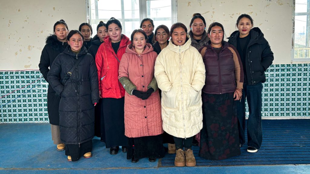 A group of women posing together indoors, wearing a mix of traditional and modern winter clothing.