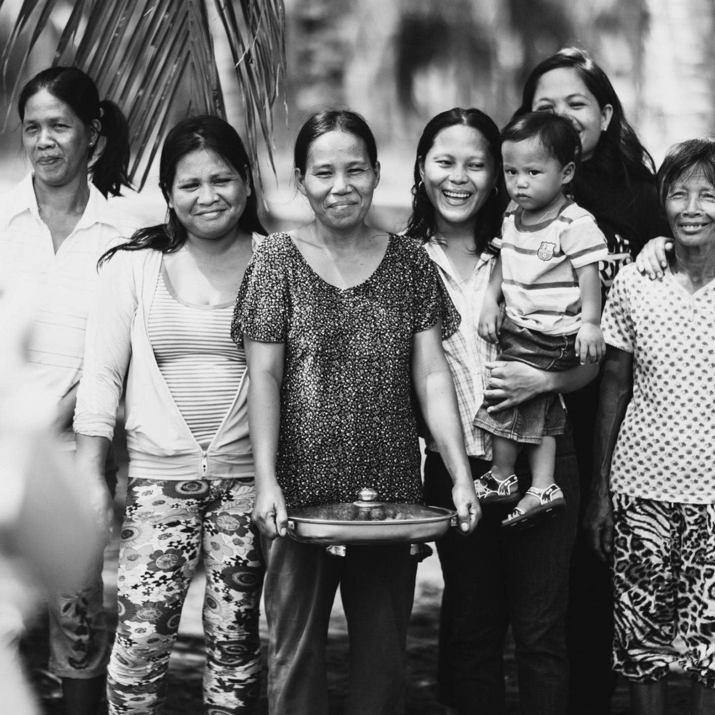 A diverse group of individuals gathered together, smiling in a natural setting.