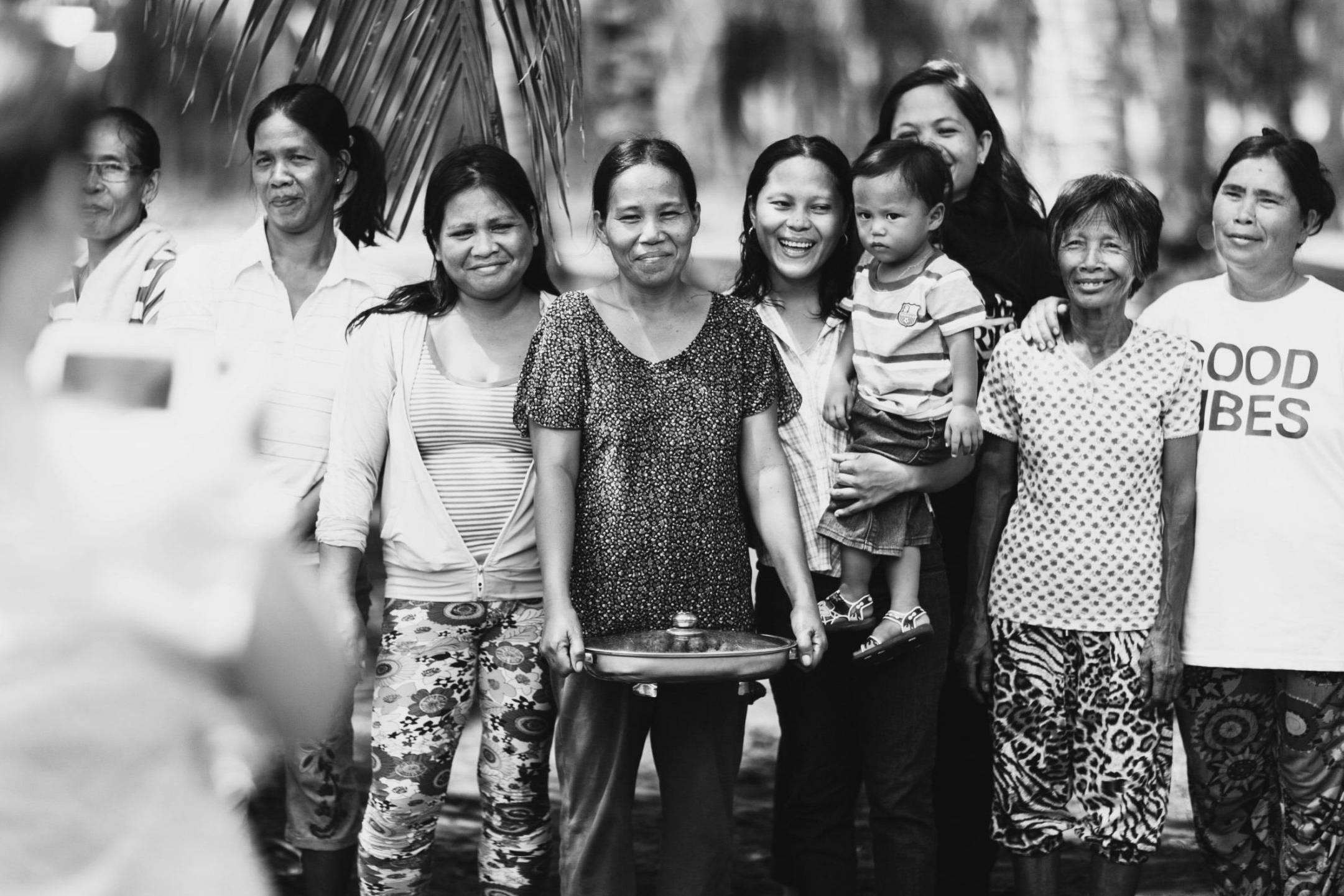 A diverse group of individuals gathered together, smiling in a natural setting.