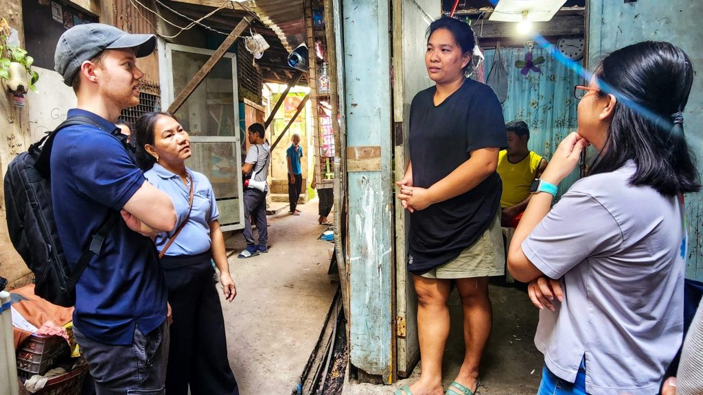 A man and three women engage in conversation in a narrow alleyway.