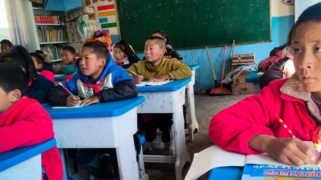 Children sitting at desks in a classroom, engaged with the lecture.