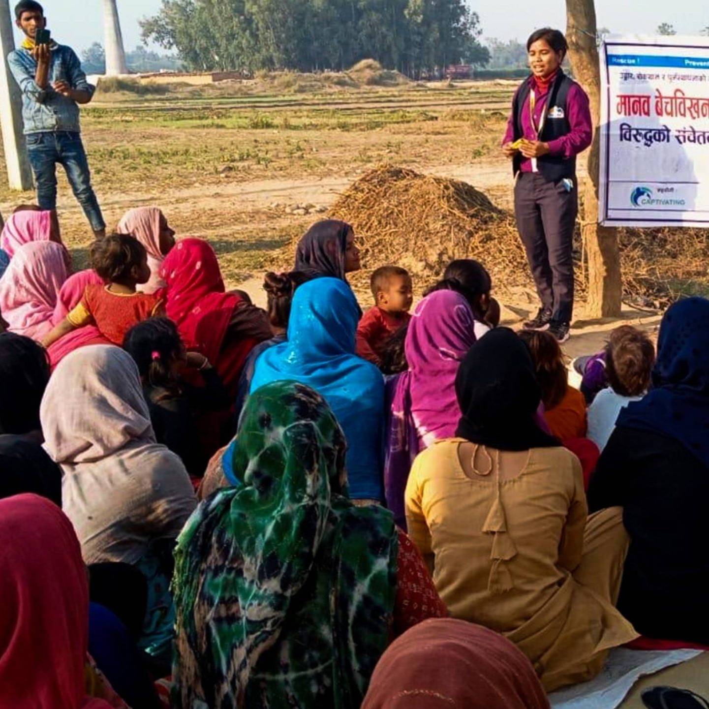 A diverse group of people on the ground, displaying a poster, actively participating in a community event.