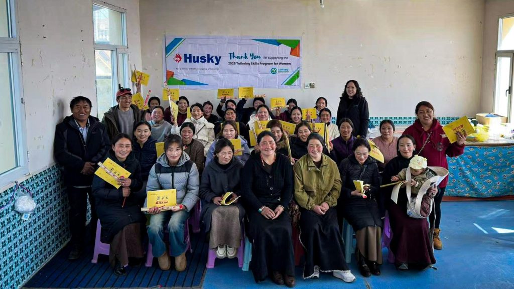 A group of people smiling and posing together, each holding a yellow book in their hands.