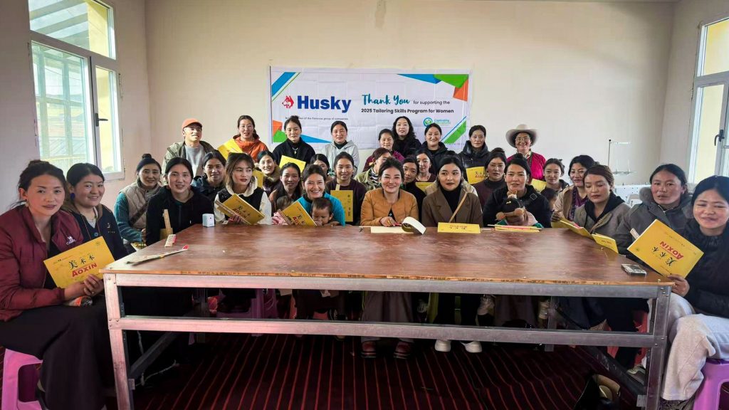 A group of people smiling and posing together, each holding a yellow book in their hands.