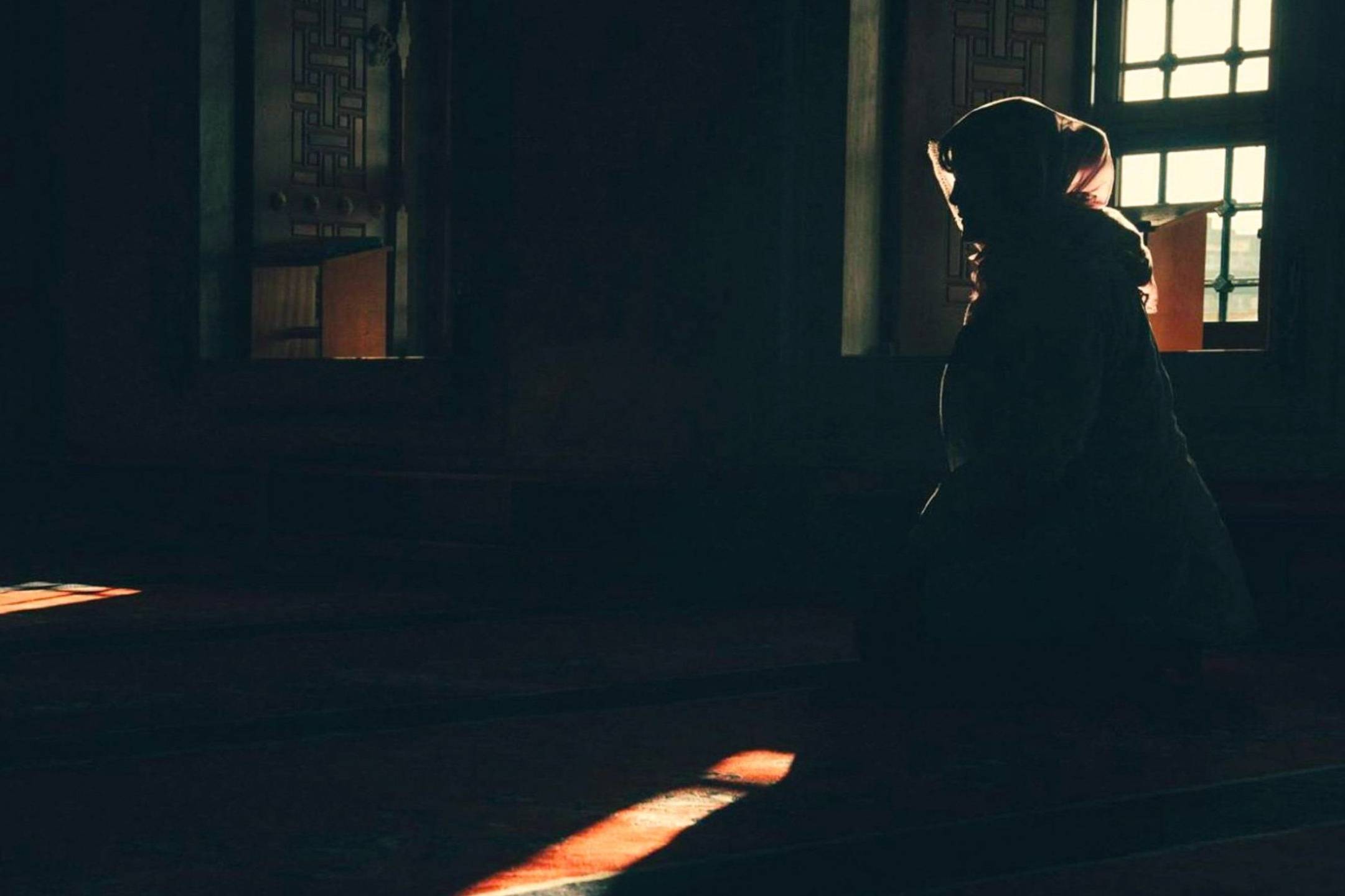 Silhouette of a woman in front of a large window, light streaming in around her.