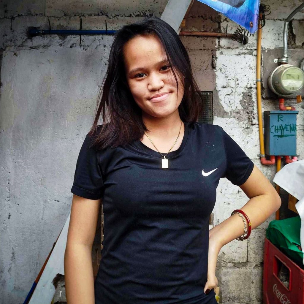 A woman wearing a black shirt stands confidently.