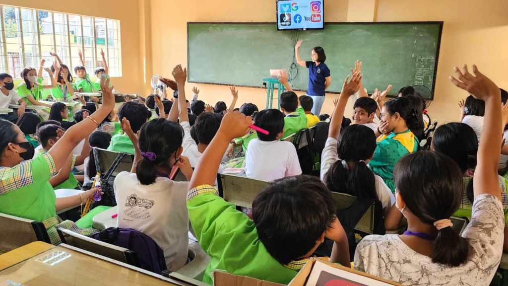 A classroom filled with children eagerly raising their hands to answer questions or participate in a discussion.