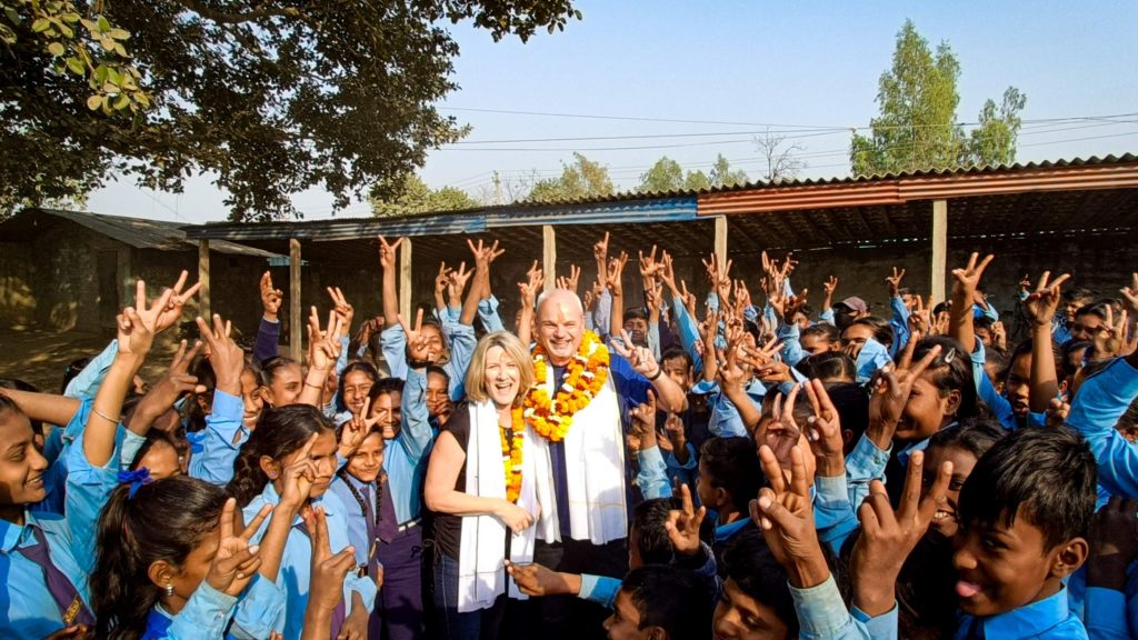 A man and woman stand with a group of children, fostering a warm and interactive atmosphere.