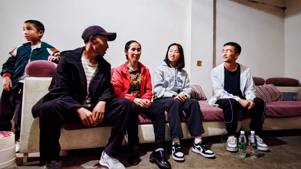 A group of five people sitting together on a couch, engaged in conversation and enjoying each other's company.