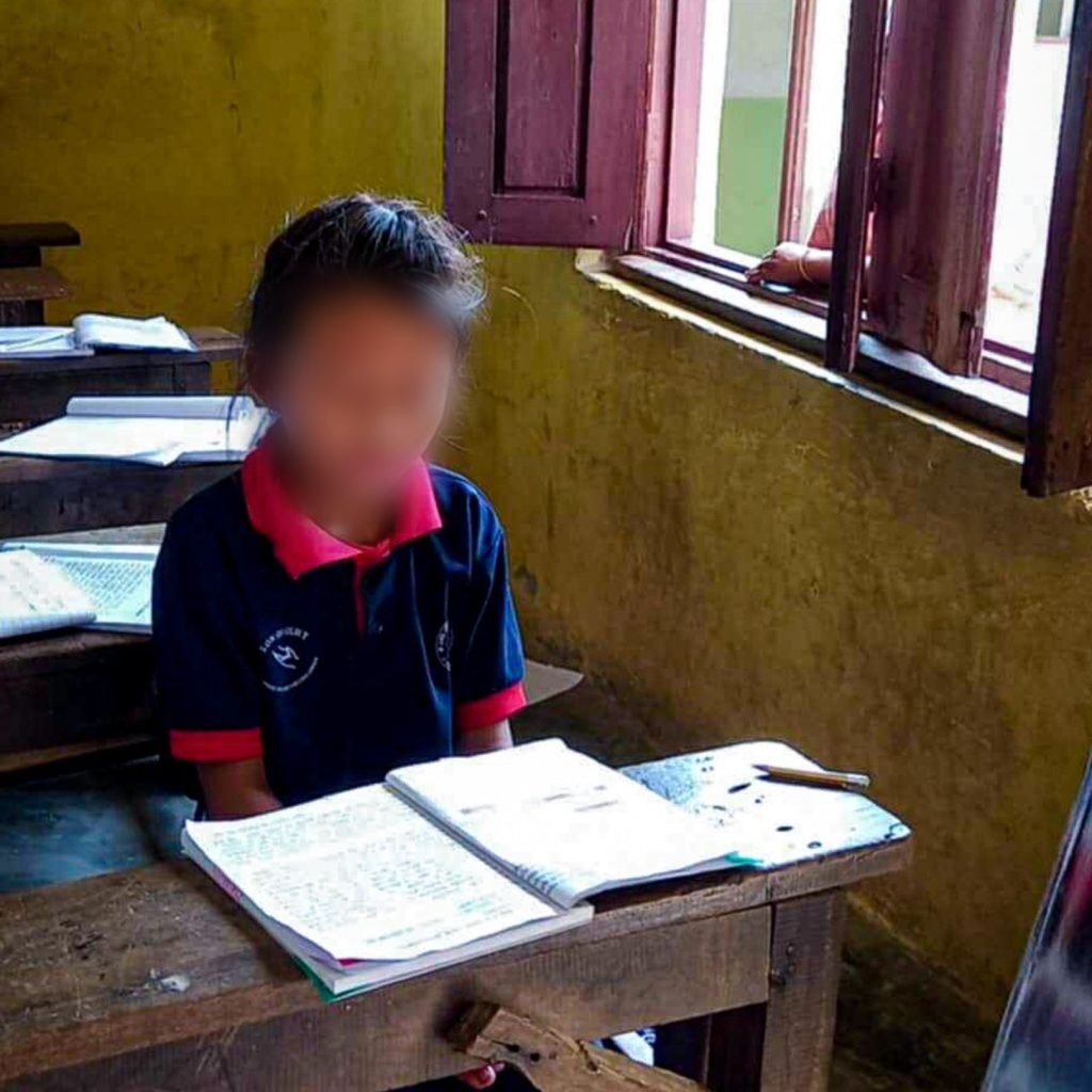 A child at a classroom desk is concentrating on their studies.