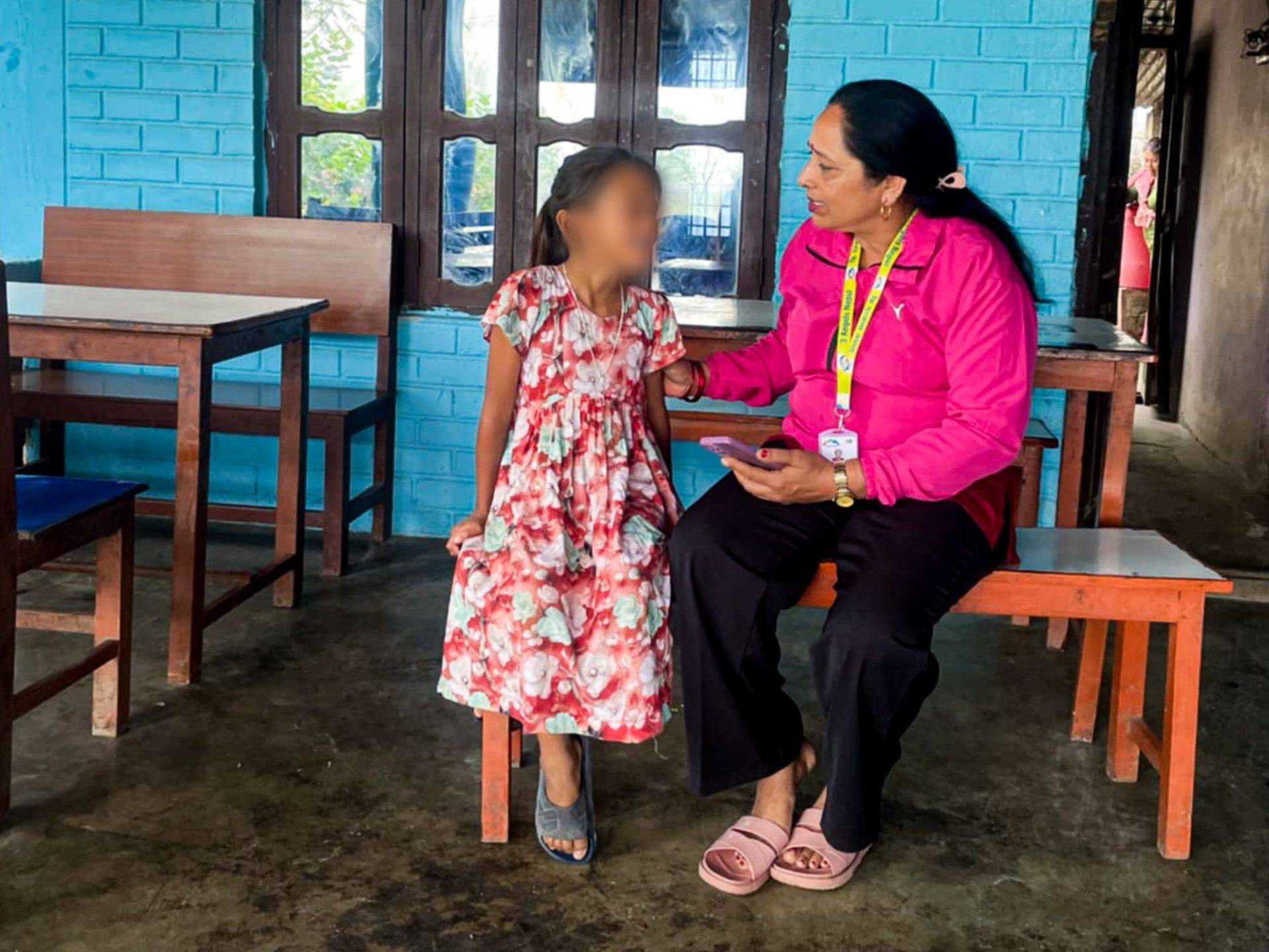 A woman and a child are seated together on a bench.
