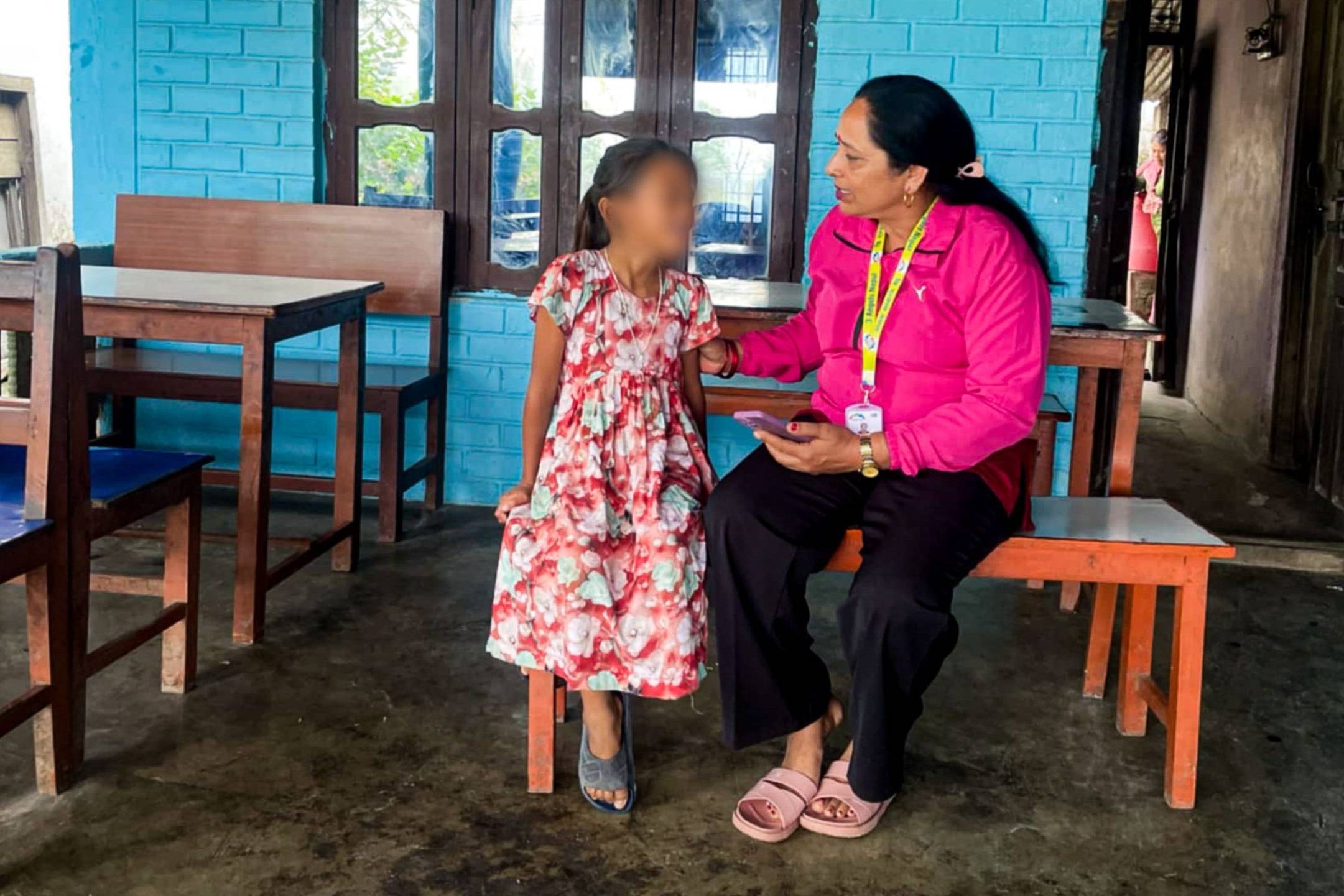 A woman and a child are seated together on a bench.