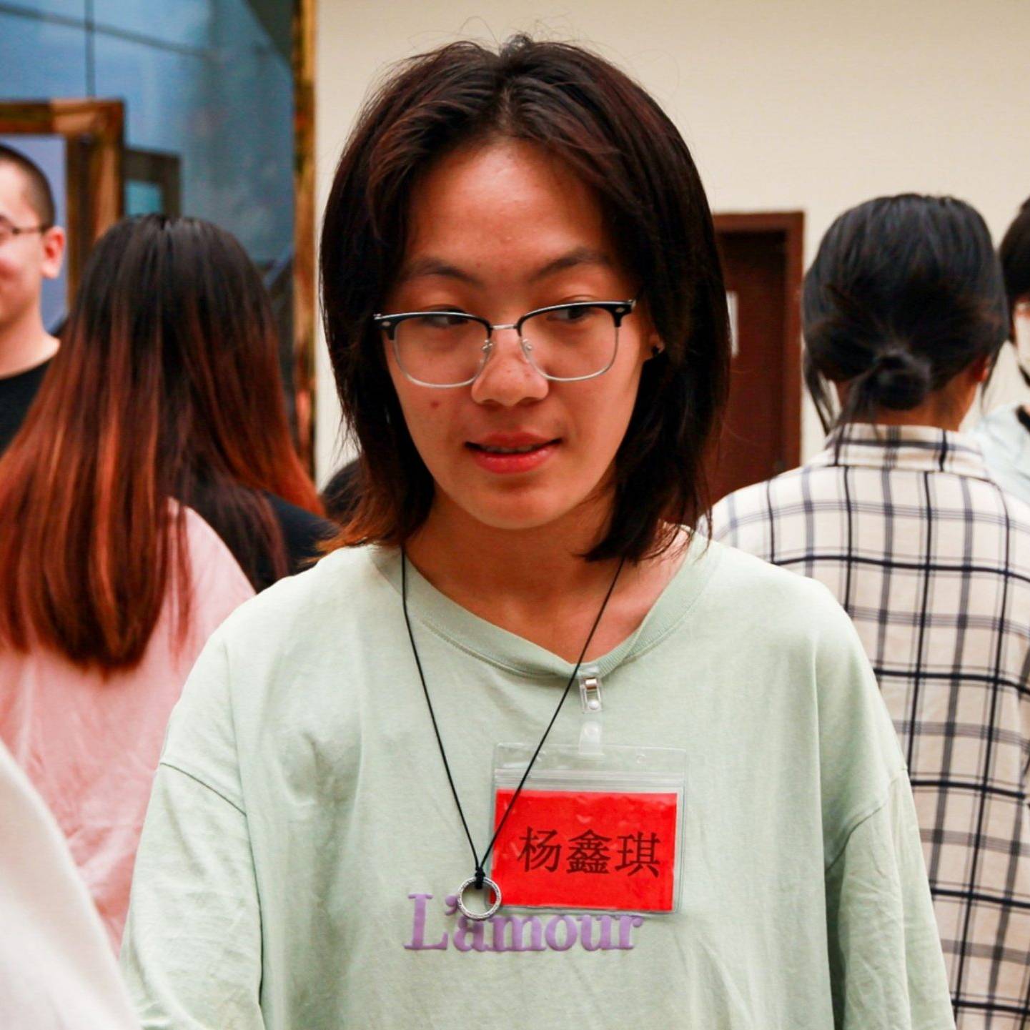A woman with glasses wearing a green shirt, smiling.