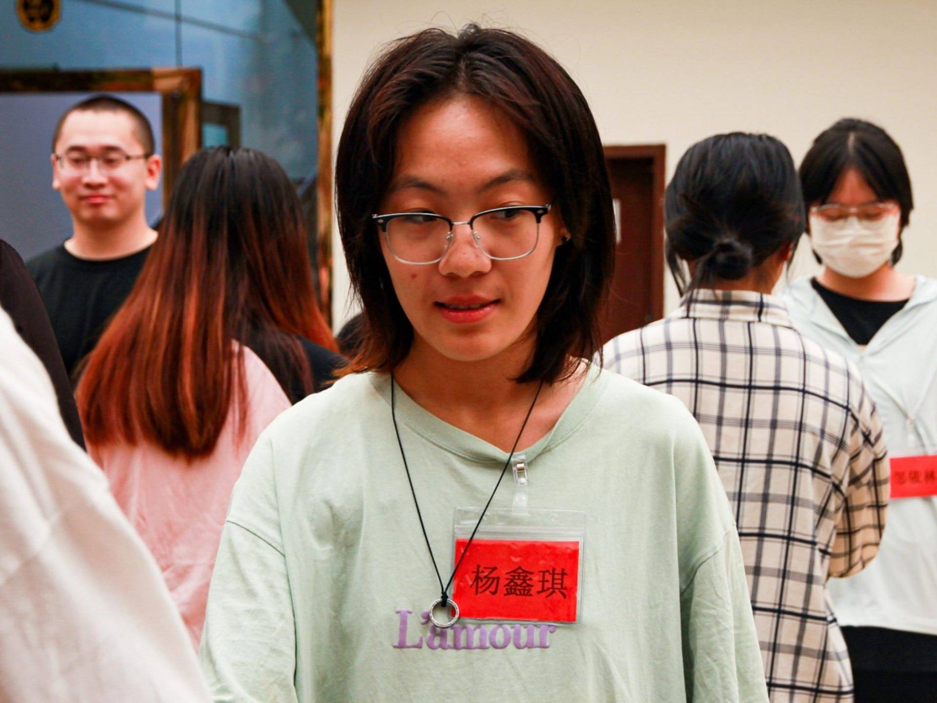 A woman with glasses wearing a green shirt, smiling.