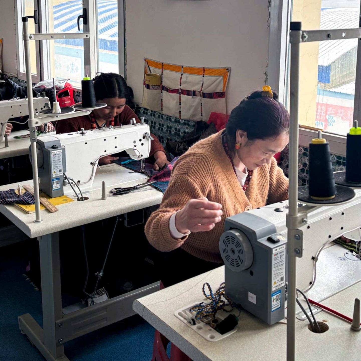 Women each operating sewing machines in a tailoring class, focused on their work.
