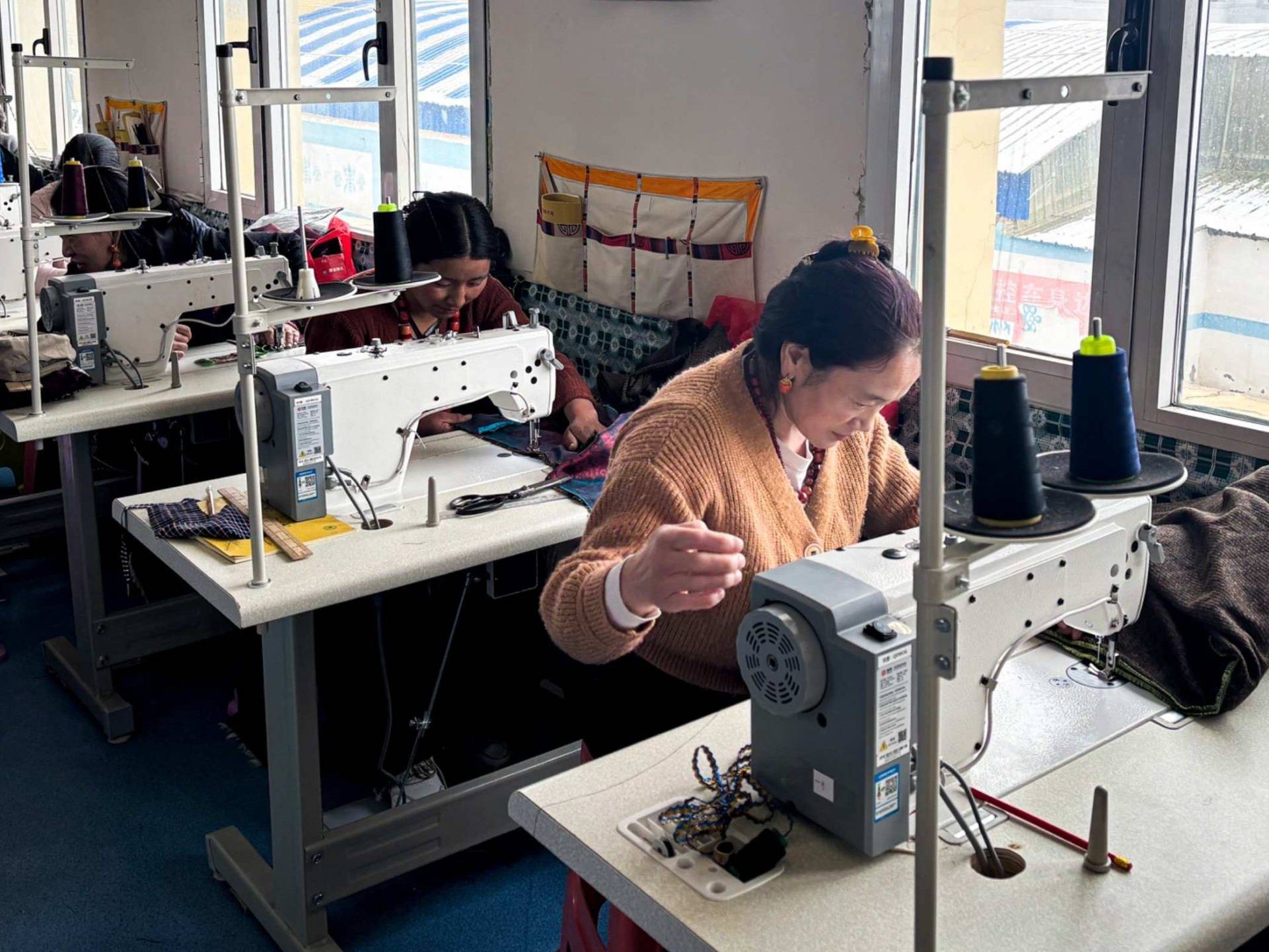Women each operating sewing machines in a tailoring class, focused on their work.