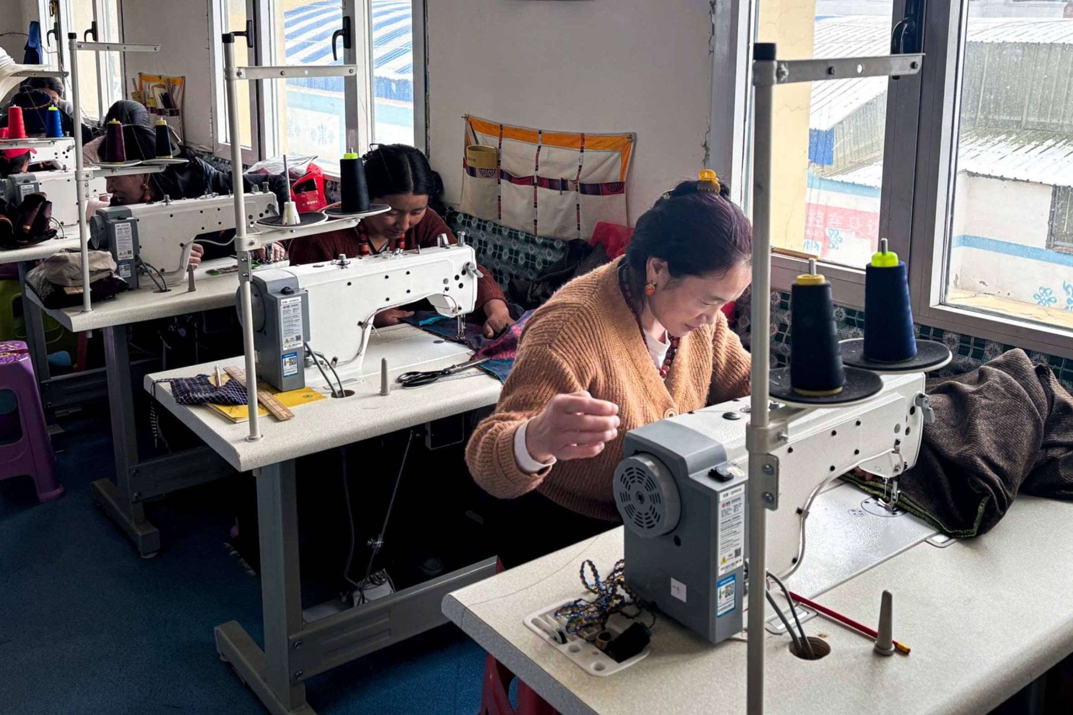 Women each operating sewing machines in a tailoring class, focused on their work.