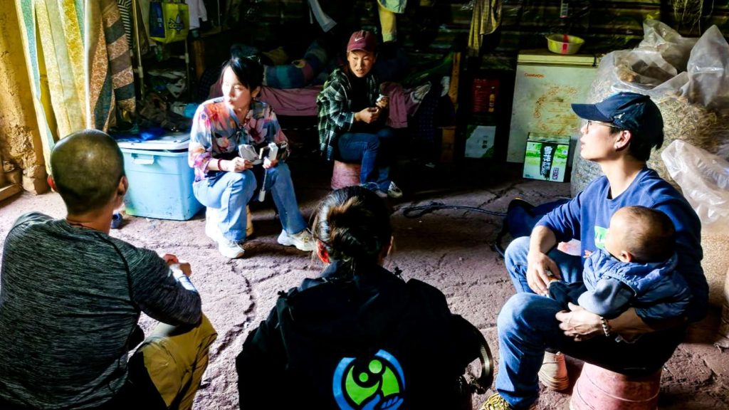 A group of people gathered around the floor in a room, engaged in conversation and discussion.