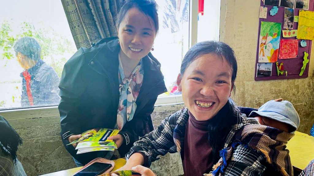 Two women smile while holding a child at a table, creating a warm and joyful moment.
