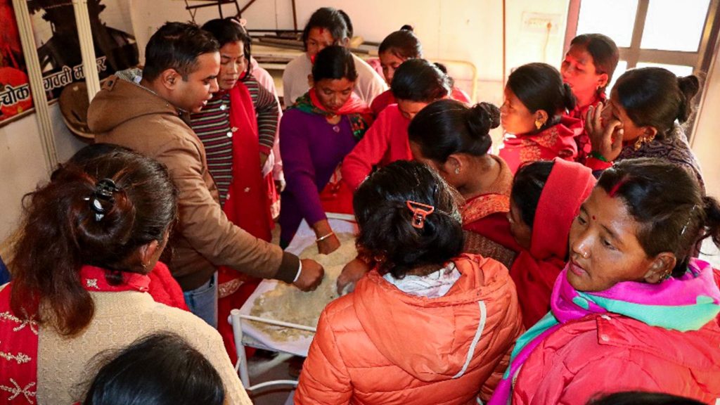A group of people gathered around a table making feed for goats.