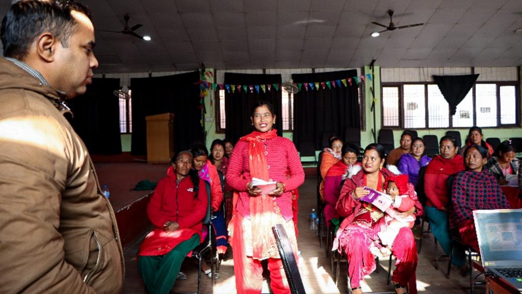 A man stands before a group of women, appearing to lead or facilitate a discussion.