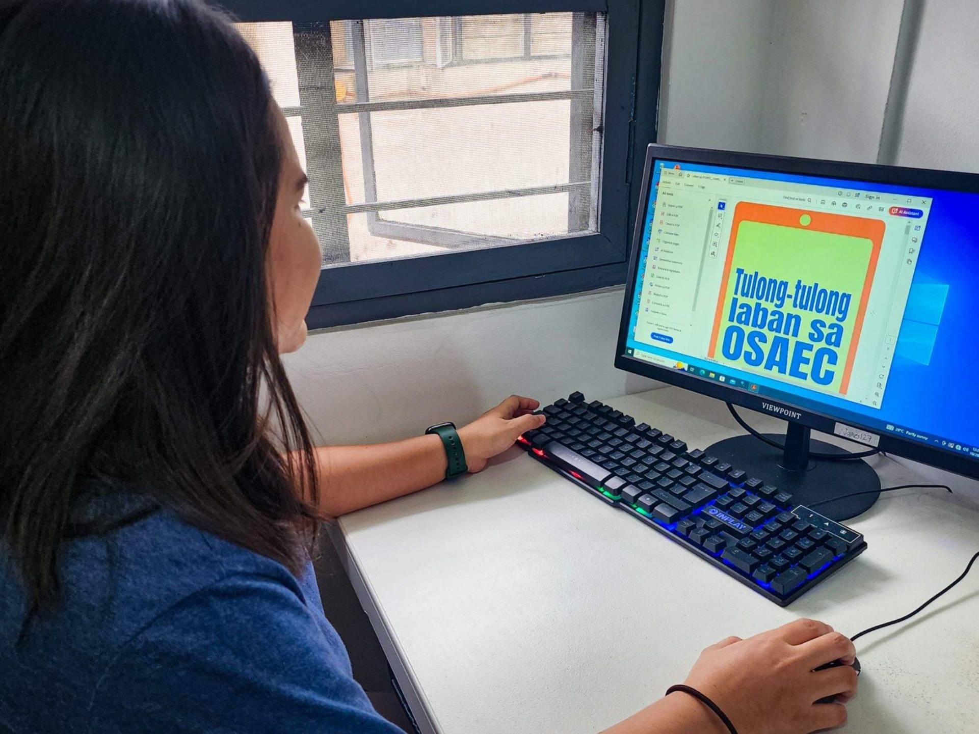 A woman focused on her computer, creating a design with graphic software in a well-lit workspace.